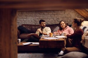 Three university students laughing together while browsing student houses in Liverpool on a laptop, planning their 2027/28 living arrangements and choosing their future housemates.